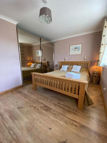 a bedroom with a wooden bed and a large mirror at Stunning 3 bedroom house with 2 bathrooms in Mansewood