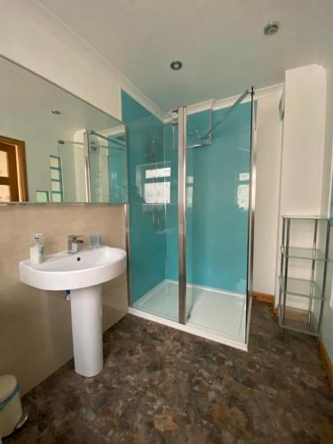 a bathroom with a sink and a glass shower at Stunning 3 bedroom house with 2 bathrooms in Mansewood