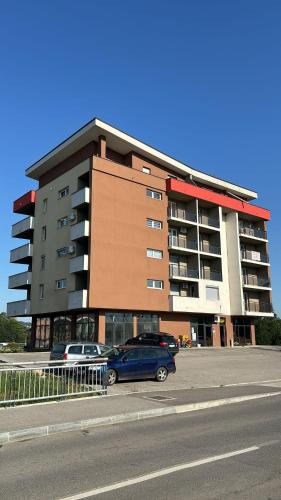 a building with cars parked in a parking lot at Apartman Nora in Teslić