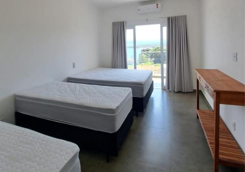 twee bedden in een kamer met een raam bij Mirante Mar de Minas - Casa para Temporada Lago de Furnas pertinho dos Canyons in São José da Barra