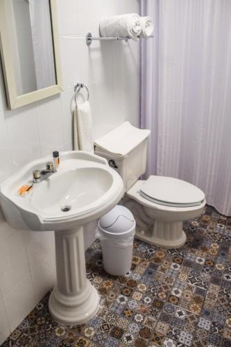 a white bathroom with a toilet and a sink at Múcara hotel in Veracruz