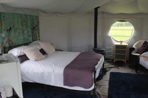 a bedroom with a bed and a window at Mousley House Farm Campsite and Glamping in Warwick