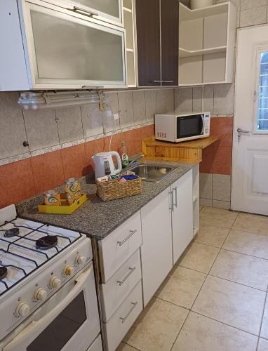 a kitchen with a stove and a sink and a microwave at De la Villa de Rada Tilly in Rada Tilly