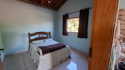 een slaapkamer met een bed en een raam bij Sítio Ramos casa da montanha in Cunha