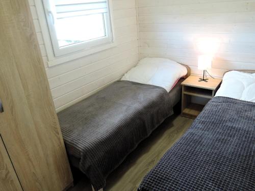 ジブヌベクにあるCottage in Dziwnówek near Baltic Sea & Lakeのベッド2台、テーブル(ランプ付)が備わる小さな客室です。