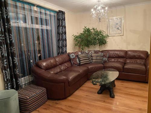 a living room with a brown leather couch and a glass table at Stunning 3 bedroom house with 2 bathrooms in Mansewood