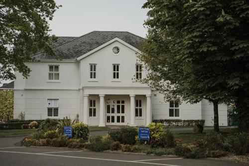 a white house with two blue signs in front of it at Crover House Hotel & Golf Club in Mountnugent