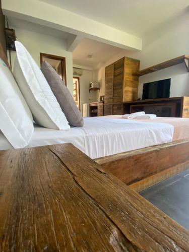 a bedroom with a large bed with white sheets and pillows at Pousada Arágua in Bombinhas