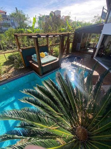a pool with a palm tree in front of a house at Pousada Arágua in Bombinhas