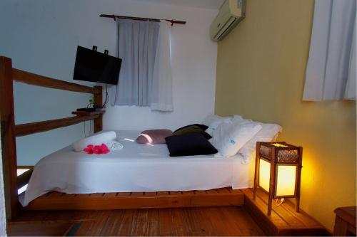 a bedroom with a white bed with a light on it at Pousada Arágua in Bombinhas