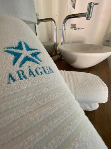 a bathroom with a sink and a bed with a towel at Pousada Arágua in Bombinhas
