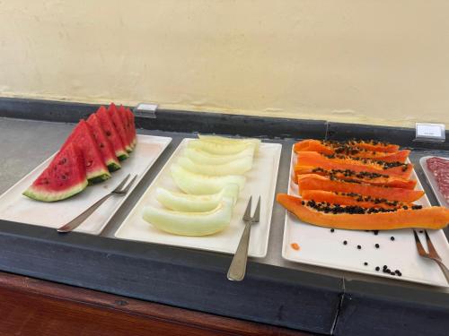a tray of food with fruits and vegetables on plates at Hotel Roma in São Sebastião