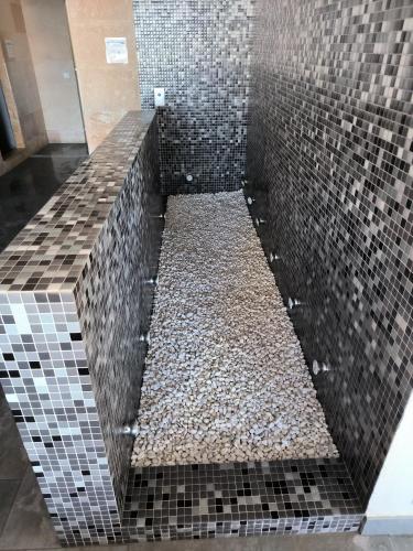 a walk in shower with black tiles and gravel at Apartamento Los Portales La Manga Spa & Gym in La Manga del Mar Menor