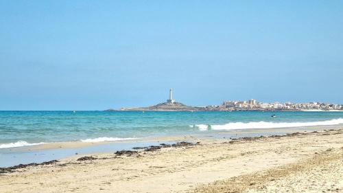 a view of a beach with a lighthouse in the distance at Apartamento Los Portales La Manga Spa & Gym in La Manga del Mar Menor
