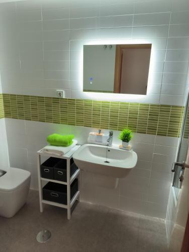 a bathroom with a sink and a toilet and a mirror at Apartamento Los Portales La Manga Spa & Gym in La Manga del Mar Menor