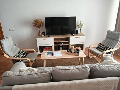 a living room with a couch and two chairs and a tv at Casa Rural El Algarrobo in Utrera