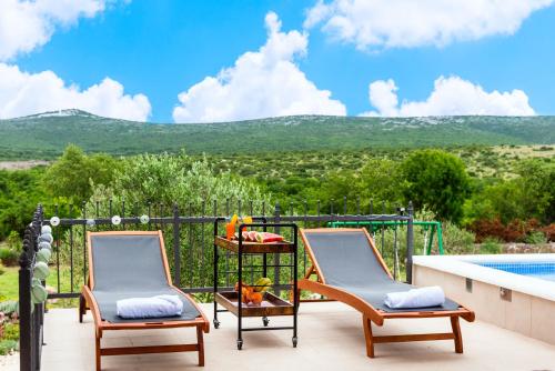 two chairs on a balcony with a view of the mountains at Villa Kiara in Unešić