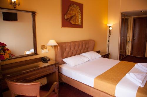 a hotel room with a bed and a desk and a mirror at Galini Palace in Athens