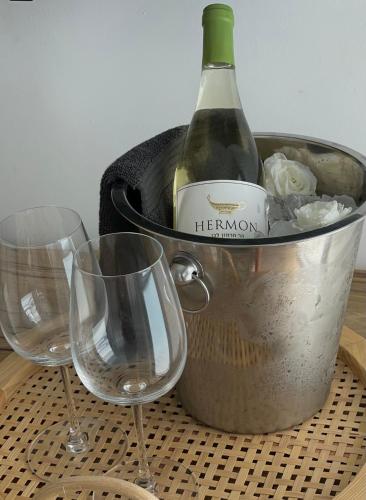 a bottle of wine in a bucket with two wine glasses at BaGiva צימרים in Giv'at Avni