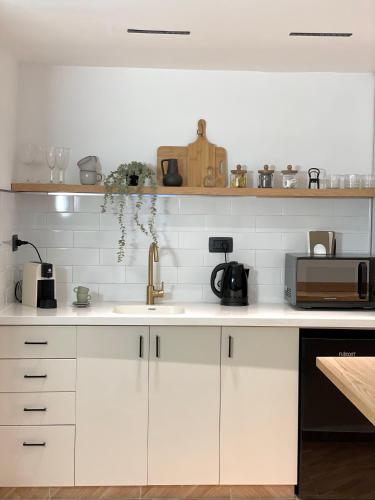 a kitchen with white cabinets and a sink at BaGiva צימרים in Giv'at Avni
