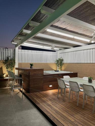 a room with a table and chairs on a wooden deck at BaGiva צימרים in Giv'at Avni