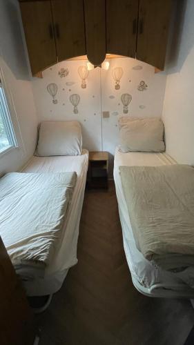 two beds in a small room with at SAYANG26 gezellige gezinsvriendelijke stacaravan op familiecamping De Vossenburcht in natuurgebied Reestdal - no workers allowed in IJhorst