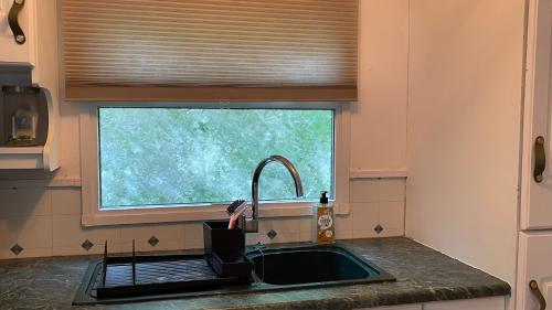 a kitchen with a sink and a window with a faucet at SAYANG26 gezellige gezinsvriendelijke stacaravan op familiecamping De Vossenburcht in natuurgebied Reestdal - no workers allowed in IJhorst