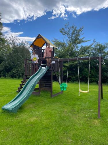 a playground with a slide and two people on it at The Lambing Lodge in Swanton Morley
