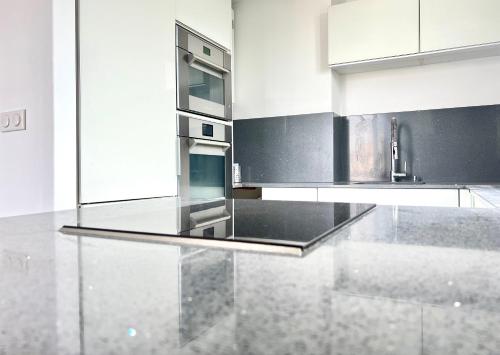 d'une cuisine équipée d'une cuisinière en acier inoxydable et de placards blancs. dans l'établissement Duplex Alfortville Gare et centre ville - Le Milhan -, à Alfortville