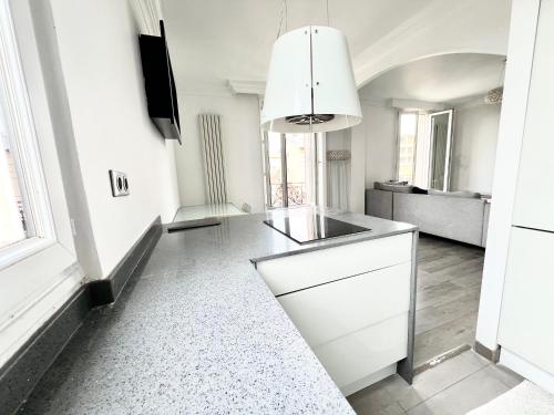 une cuisine avec des armoires blanches et un évier dans l'établissement Duplex Alfortville Gare et centre ville - Le Milhan -, à Alfortville