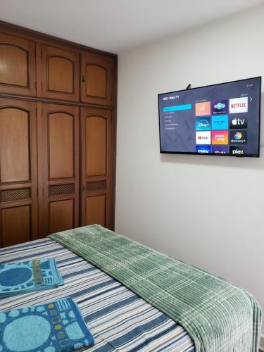 a bedroom with a bed with a tv on the wall at Pousada Monte Gerizim in Sao Paulo