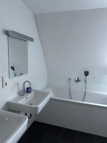 a white bathroom with a sink and a bath tub at Al Nafurah Apartments in Munich