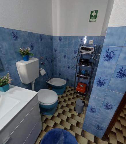 a blue tiled bathroom with a toilet and a sink at Casa do Neto Tiago in Fundão