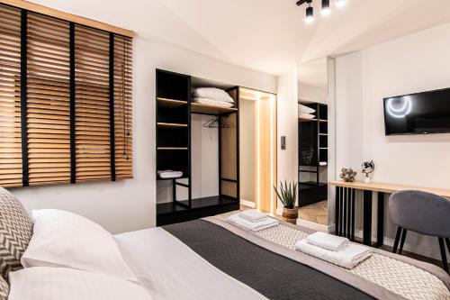 a bedroom with a bed and a desk and a television at VERDANT by Cozy Stories in Alexandroupoli