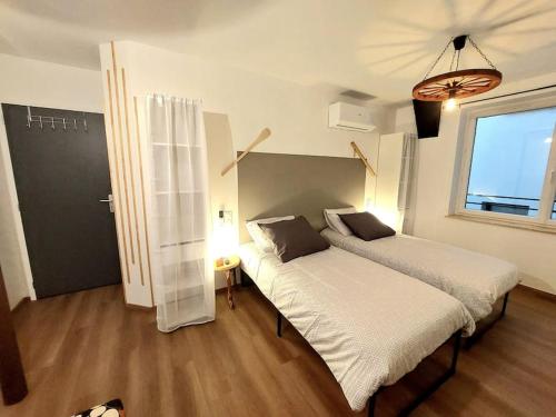 ein Schlafzimmer mit zwei Betten und einem Fenster in der Unterkunft Le Caladou ! T3 classé 3 étoiles - Centre ville in Espalion