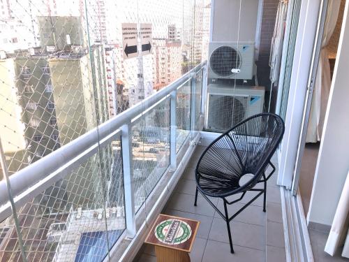 a balcony with a black chair and a window at Unlimited - Frente ao Mar. Apt todo mobiliado. in Santos