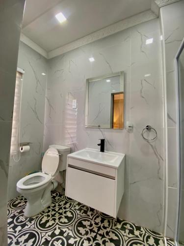 a bathroom with a toilet and a sink and a mirror at Central Gabs Oasis: 2BR-Retreat in Gaborone