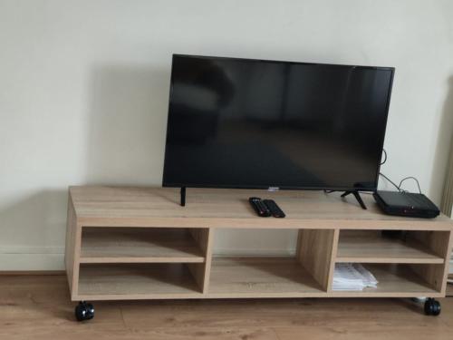 - une télévision à écran plat sur un support en bois dans l'établissement l'Harmony, à La Tronche