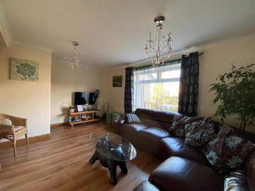 a living room with a leather couch and a table at Stunning 3 bedroom house with 2 bathrooms in Mansewood