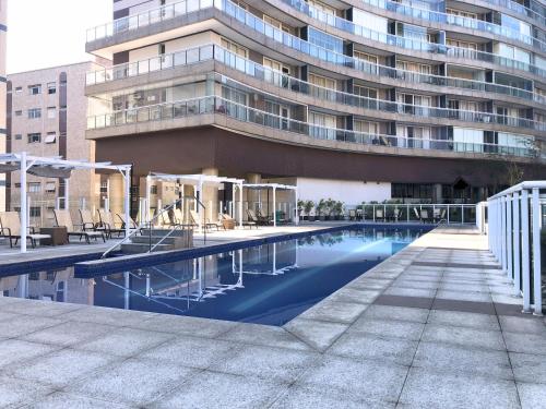 a swimming pool in front of a tall building at Unlimited - Frente ao Mar. Apt todo mobiliado. in Santos