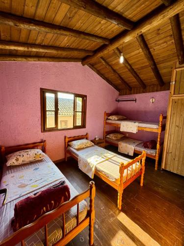 a room with three beds and a wooden ceiling at Rosatrip Surf Bungalows in Praia do Rosa