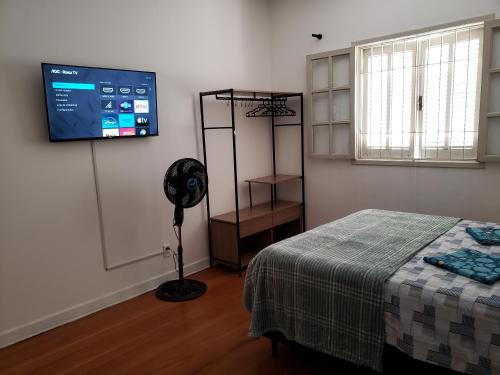 a room with a bed and a flat screen tv at Pousada Monte Gerizim in Sao Paulo