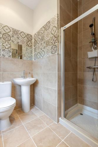 a bathroom with a shower and a toilet and a sink at Riverside Townhouse Antrim in Antrim