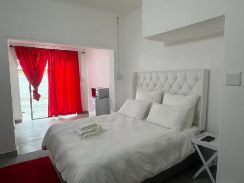 a bedroom with a large white bed with a red window at No 1 Guest house in Cape Town