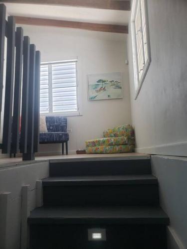 a room with stairs and a chair and a window at The Red Door Beach House, Buye Beach in Cabo Rojo