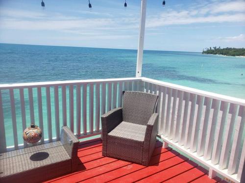 a balcony with two chairs and the ocean at The Red Door Beach House, Buye Beach in Cabo Rojo