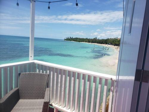 a balcony with a view of the ocean and a beach at The Red Door Beach House, Buye Beach in Cabo Rojo