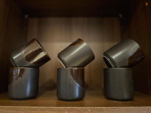 three metal cups sitting on a wooden shelf at Birmingham City Stay Apartments in Birmingham