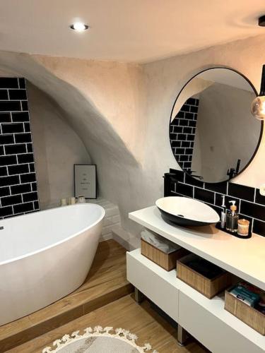 La salle de bains est pourvue d'une grande baignoire blanche et d'un miroir. dans l'établissement Cosy Studio near Eiffel Tower, à Paris