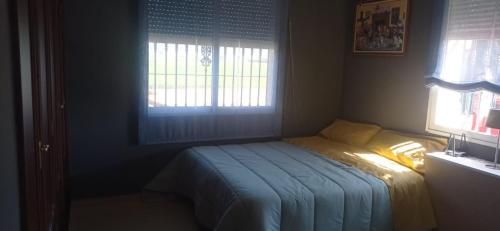 un piccolo letto in una camera da letto con due finestre di Hacienda el chorlo a Encinarejo De Córdoba